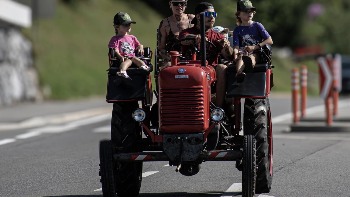 Roter Traktor mit Fahrerin und drei Kindern auf einer Stra&szlig;e bei Oldtimertreffen Langen 2025