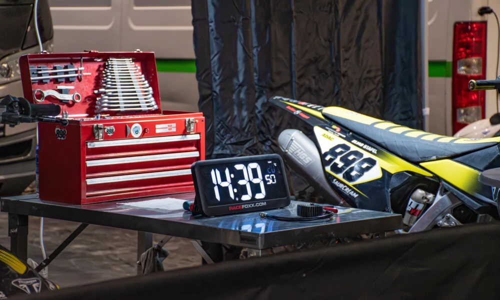 Werkzeugkiste und digitale Uhr an einem Tisch, Motorrad im Hintergrund, Motorradwelt 2026