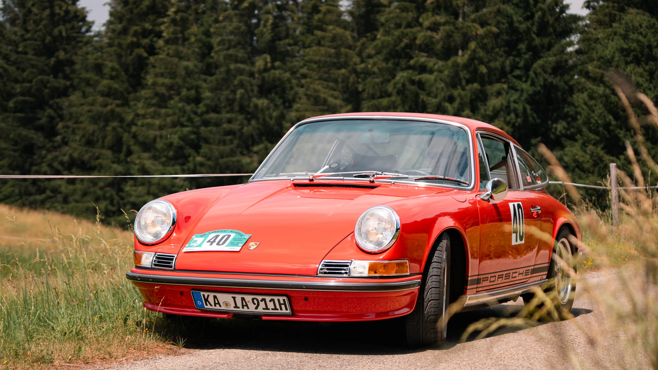 Porsche 911 auf einer Landstraße während der Lindau-Klassik Rallye 2023 Roter Porsche 911, aufgenommen bei der Lindau-Klassik Rallye in der Natur