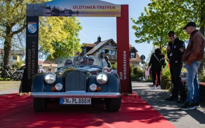 Oldtimer Treffen 2026 mit einem Morgan Roadster auf rotem Teppich.