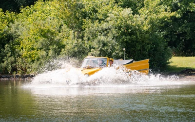 Gelber Amphibienfahrzeug im Wasser spritzt beim Fahren auf dem Bodensee