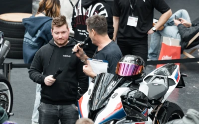 Mann spricht mit Mikrofon neben BMW-Motorrad auf Motorradwelt 2026