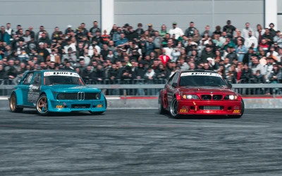 Zwei BMW Rennautos, turquoise und rot, w&auml;hrend einer Drift-Show auf der Tuning World Bodensee 2026.