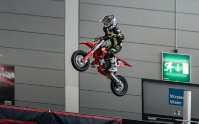 Ein Kind springt mit einem roten Mini-Motorrad auf einer Messe