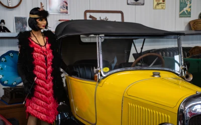 Mannequin in rotem Kleid steht neben gelbem Oldtimer im Automuseum