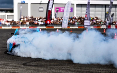 Sportwagen f&uuml;hrt Driftman&ouml;ver mit Rauchentwicklung auf der Tuning World 2025
