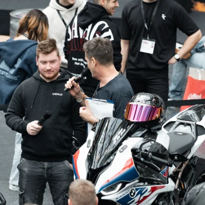 Mann spricht mit Mikrofon neben BMW-Motorrad auf Motorradwelt 2026