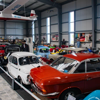 Alter Automobil-Showroom mit mehreren Fahrzeugen und einem Flugzeug in der Decke