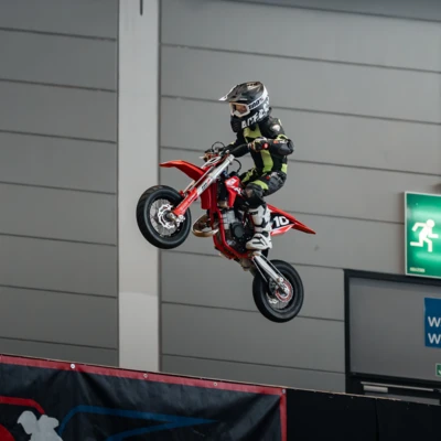 Ein Kind springt mit einem roten Mini-Motorrad auf einer Messe