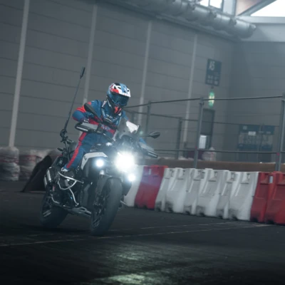 Motorradfahrer auf einer BMW f&auml;hrt mit beleuchtetem Fahrzeug in einer Halle