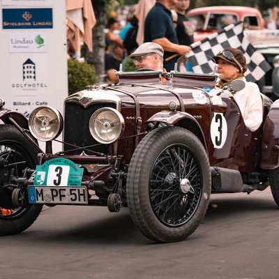 Oldtimer bei der Lindau-Klassik Rallye, Fahrer mit Flagge