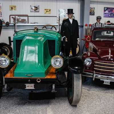 Gr&uuml;nes Oldtimer-Auto und roter Wagen in Automuseum L&ouml;mmenschwil