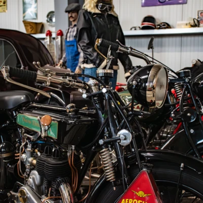 Diverse Motorr&auml;der in einem Automuseum, darunter ein schwarzes Modell mit Details