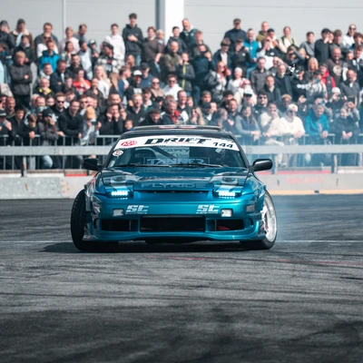 Blaues Drift-Auto w&auml;hrend einer Veranstaltung mit Publikum im Hintergrund