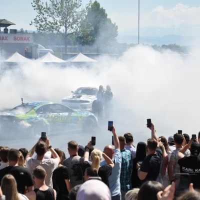 Rennwagen f&uuml;hren Driftman&ouml;ver inmitten einer Menschenmenge auf der Tuning World 2025