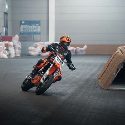 Motorradfahrer in schwarzer und orangener Gear f&auml;hrt auf einer Strecke bei der Motorradwelt 2026.