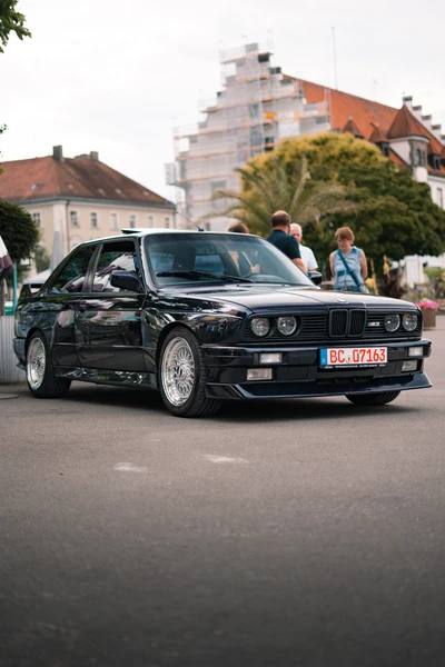 Schwarzer BMW in der Umgebung der Lindau-Klassik Rallye, mit Zuschauern.
