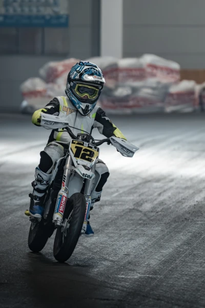 Junge f&auml;hrt auf einem wei&szlig;en Motocross-Motorrad auf einer Messe.