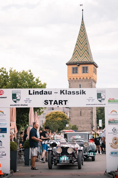 Oldtimer startet bei der Lindau-Klassik Rallye vor historischem Turm.