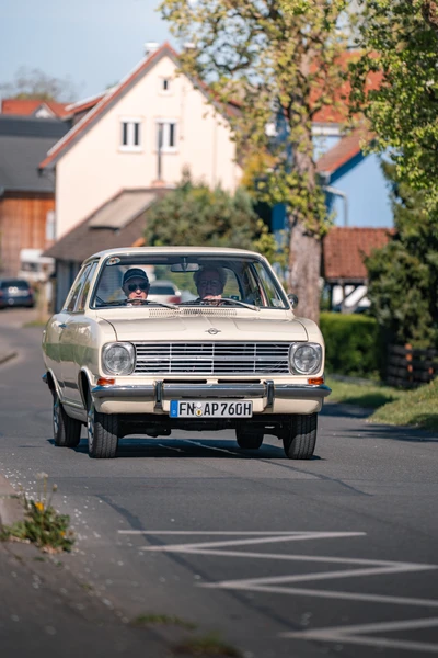Oldtimer f&auml;hrt auf einer Stra&szlig;e in Wasserburg, zwei Personen im Auto sichtbar.