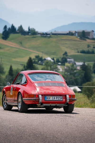 Roter Porsche 911 f&auml;hrt auf einer malerischen Stra&szlig;e bei der Lindau-Klassik Rallye