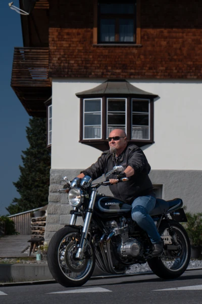 Mann f&auml;hrt auf Kawasaki-Motorrad neben einem Wohnhaus