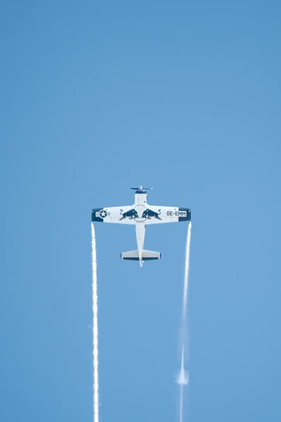 Ein Flugzeug mit Red Bull-Lackierung fliegt senkrecht in den blauen Himmel.