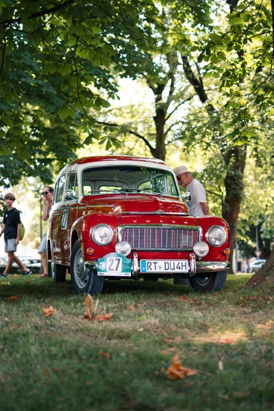 Roter Oldtimer auf der Lindau-Klassik Rallye, umgeben von B&auml;umen