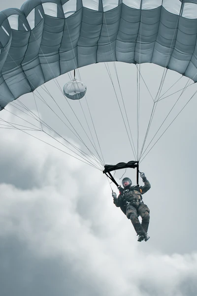 Frau im Fallschirm, schwebt &uuml;ber Wolken w&auml;hrend eines Sprungs.
