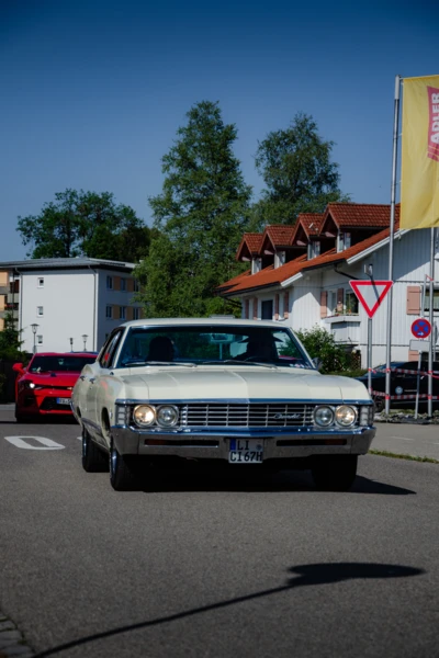 Wei&szlig;er Oldtimer f&auml;hrt durch eine Stra&szlig;e beim American-Dream-V8 Treffen in Lindenberg