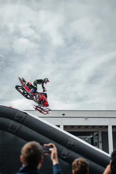 Sportler springt auf Schnee-Motorrad von einer Rampe bei Tuning World Bodensee 2026