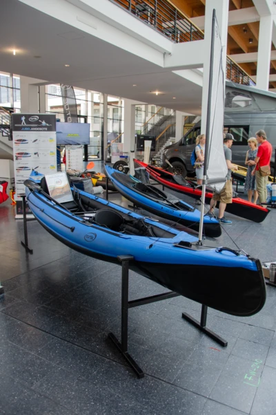 Blaue Kajaks auf einer Messe mit St&auml;nden und Besuchern in Friedrichshafen