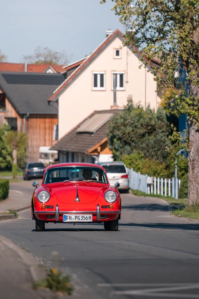 Roter Oldtimer f&auml;hrt entlang einer Wohnstra&szlig;e auf dem Oldtimertreffen Wasserburg 2026