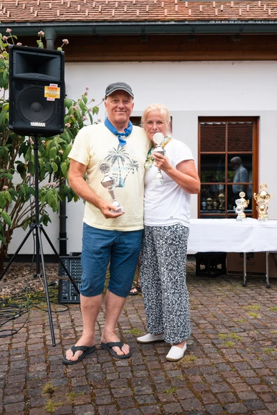 Paar h&auml;lt Pokale bei der Lindau-Klassik Rallye in einer Gartenumgebung