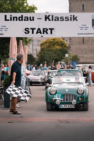 Gr&uuml;ner Sportwagen beim Start der Lindau-Klassik Rallye, Blockade mit Schachbrettflagge.