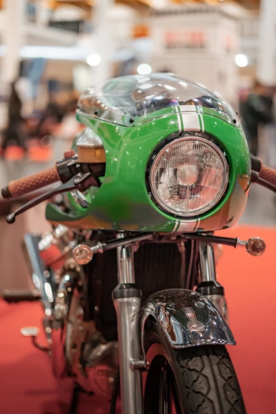 Gr&uuml;ne Rennmaschine mit Kettenantrieb und klarer Verkleidung auf rotem Messeboden.