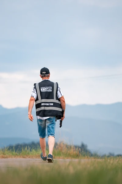 Person in Sicherheitsweste geht auf einem Weg mit Berglandschaft
