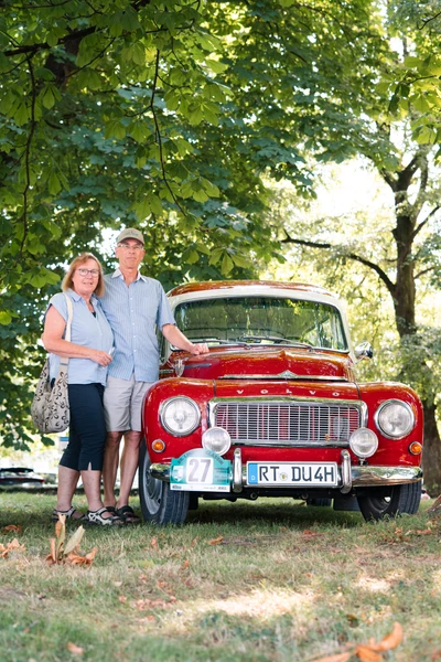 Paar posiert vor einem roten Oldtimer w&auml;hrend der Lindau Klassik Rallye