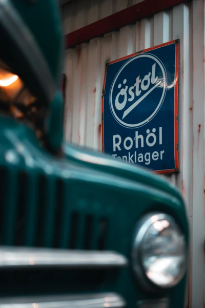 Nahaufnahme eines Fahrzeugs vor einem &Ouml;ltankschild in der Motorworld M&uuml;nchen