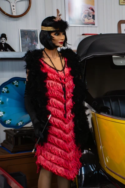 Automuseum Lömmenschwil, Hürlimann, Schweiz Mannequin in rotem Kleid steht neben gelbem Oldtimer im Automuseum