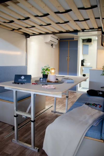 Wohnwagen-Innenansicht auf der Adventure Southside 2025. Gemütlicher Innenraum eines Wohnwagens mit Tisch, Couch und Pflanzen. Adventure Southside 2025.