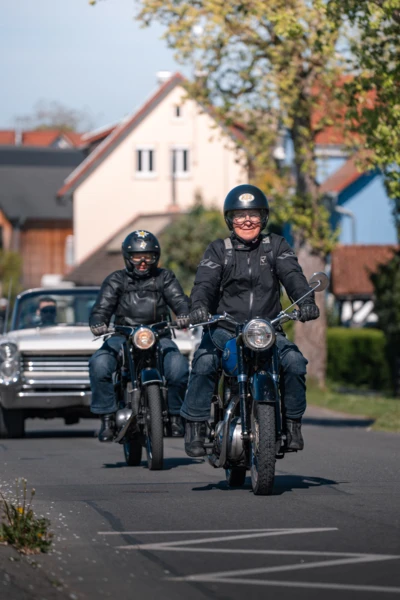 Zwei Motorr&auml;der fahren auf einer Stra&szlig;e bei einem Oldtimertreffen.
