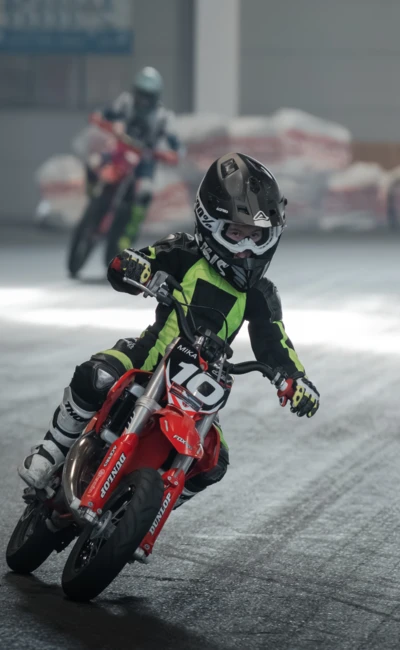 Junge auf einem roten Mini-Motorrad, f&auml;hrt auf einer Messe.