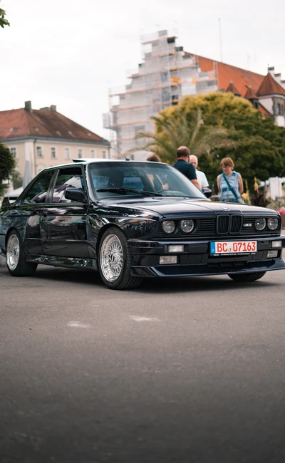 Schwarzer BMW in der Umgebung der Lindau-Klassik Rallye, mit Zuschauern.