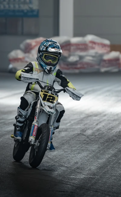 Junge f&auml;hrt auf einem wei&szlig;en Motocross-Motorrad auf einer Messe.