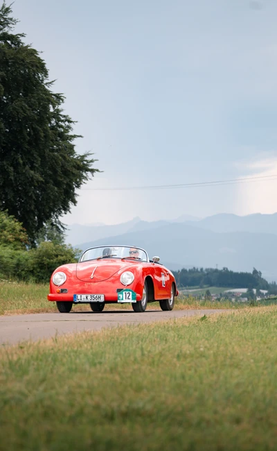 Roter Sportwagen f&auml;hrt auf einer Landstra&szlig;e w&auml;hrend der Lindau-Klassik Rallye.