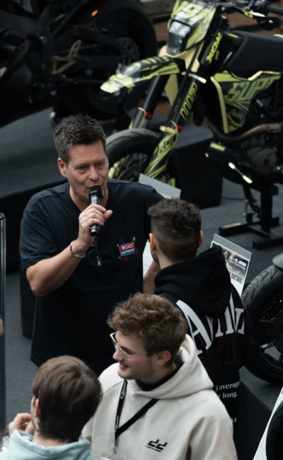 Mann spricht zu einer Gruppe von Personen auf der Motorradwelt 2026 in Friedrichshafen