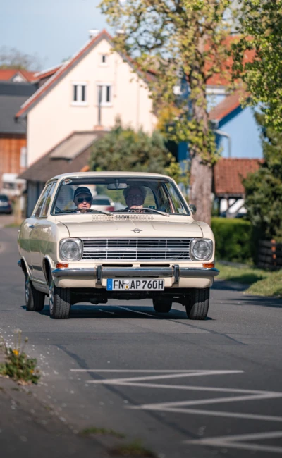 Oldtimer f&auml;hrt auf einer Stra&szlig;e in Wasserburg, zwei Personen im Auto sichtbar.