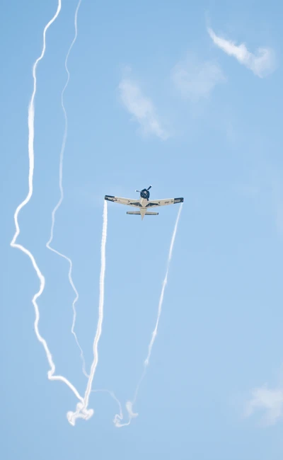 Flugzeug f&uuml;hrt Luftakrobatik mit Rauchspuren am Himmel aus