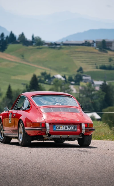 Roter Porsche 911 f&auml;hrt auf einer malerischen Stra&szlig;e bei der Lindau-Klassik Rallye